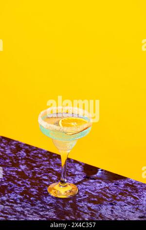 Süß-saurer Margarita-Cocktail mit Orangenscheibe vor lebhaftem gelbem Hintergrund Stockfoto