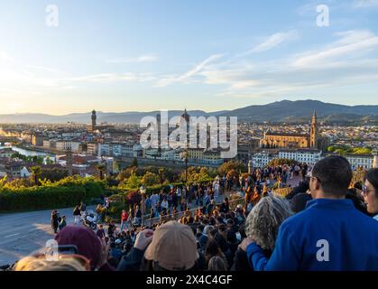 Eine Menge Touristen auf den Stufen der Piazzale Michelangelo in Florenz in der Toskana, Italien bei Sonnenuntergang. Mit Blick auf die Skyline von Florenz und den Dom. Stockfoto