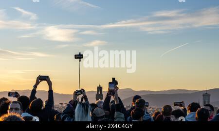 Eine Menge Touristen hält Telefone über dem Kopf, um Fotos von der Skyline von Florenz am Piazzale Michelangelo zu machen. Ein Beispiel für Übertourismus. Stockfoto