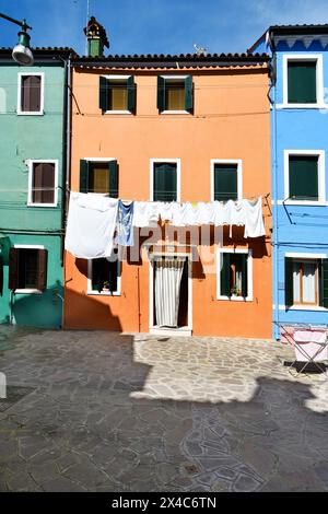 Burano, Italien - 17. April 2024: Blick auf die bunten Häuser auf der Insel in der Lagune von Venedig, frisch gewaschene Wäsche zum Trocknen Stockfoto