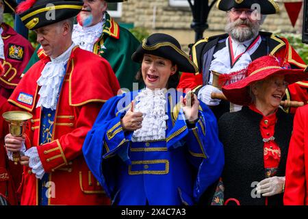 Stadtschreier (Pagen und Pagen in bunten Flechtbrillen und Uniformen), die in Gruppe, Lächeln und Posen stehen - Ilkley, West Yorkshire, England, Großbritannien. Stockfoto