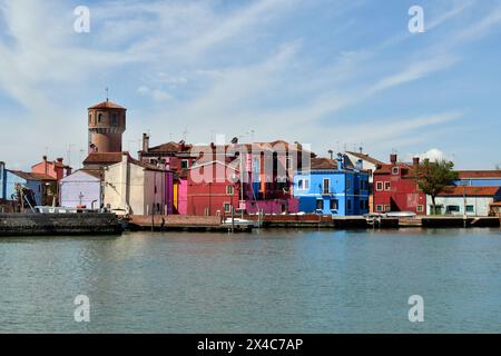 Burano, Italien - 17. April 2024: Blick auf die farbenfrohen Häuser und den historischen Wasserturm auf der Insel in der Lagune von Venedig Stockfoto