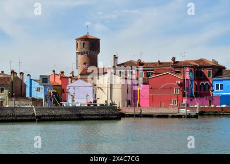 Burano, Italien - 17. April 2024: Blick auf die farbenfrohen Häuser und den historischen Wasserturm auf der Insel in der Lagune von Venedig Stockfoto