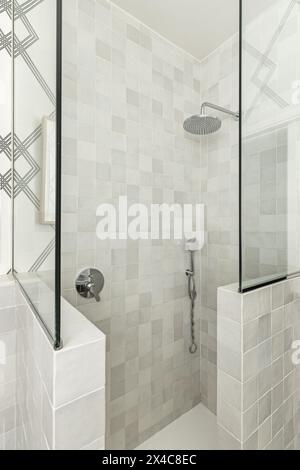 Duschkabine in einem neu renovierten Badezimmer mit kombinierten Wänden aus Fliesen und gehärtetem Glas Stockfoto
