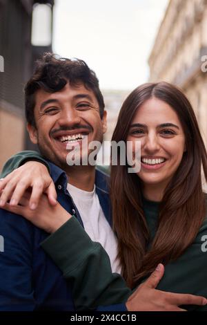 Portrait junger multirassischer Paare, die glücklich lächelndes Gesicht auf der Straße umarmen. Freunde fröhlich umarmen. Stockfoto