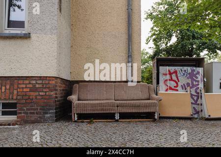 Eine alte Couch auf dem Bürgersteig, sperriger Abfall auf der Straße, sperriger Abfall in der Stadt Stockfoto