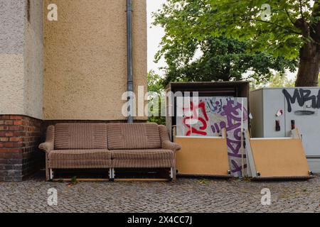 Eine alte Couch auf dem Bürgersteig, sperriger Abfall auf der Straße, sperriger Abfall in der Stadt Stockfoto
