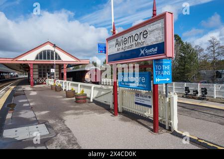 Bahnsteigschild für den viktorianischen Aviemore Bahnhof und den Royal Scotsman, der den Bahnhof verlässt. Stockfoto