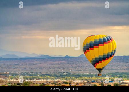 USA, New Mexico, Albuquerque. Heißluftballon, der bei Sonnenaufgang über die Stadt fliegt. Stockfoto