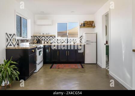 Modernes Bohemian Desert Haus weiß schwarze Küche mit Fliesen und poliertem Betonboden Stockfoto