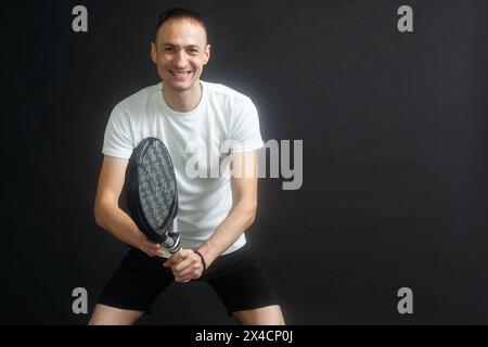 Porträt eines Mannes, der Paddeltennis spielt, in Position, um einen schwarzen, isolierten Hintergrund zu treffen. Vorderansicht. Stockfoto