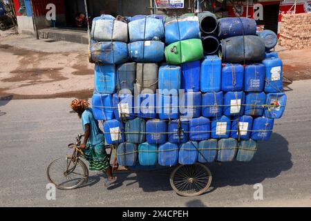 Dhaka, Dhaka, Bangladesch. Mai 2024. Ein Arbeiter trägt Plastikfässer in einem dreirädrigen Van in Sadarghat in Dhaka. Im Allgemeinen werden diese Fässer für den Öltransport verwendet. (Kreditbild: © Syed Mahabubul Kader/ZUMA Press Wire) NUR REDAKTIONELLE VERWENDUNG! Nicht für kommerzielle ZWECKE! Stockfoto