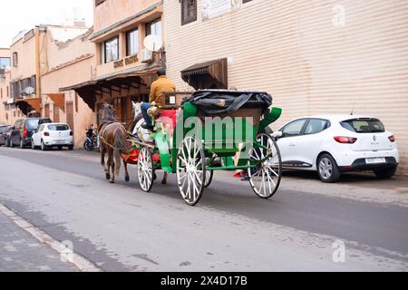 Touristen und Einheimische fahren in Pferdekutschen durch lebhafte Straßen Marrakesch, authentisches und lebendiges Stadtleben Afrikanisches Königreich Marokko, Marrakesch Stockfoto