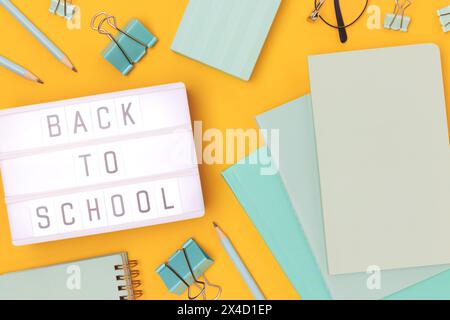 Zurück zur Schule. Leuchtkasten mit Buchstaben und mintfarbenen Briefpapier auf gelbem Hintergrund. Stockfoto