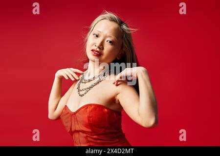 Eine attraktive asiatische Frau in einem leuchtenden roten Kleid posiert aktiv für einen Schuss. Stockfoto