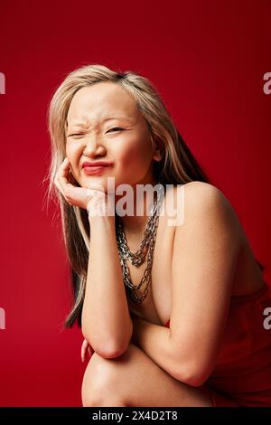 Asiatische Frau in einem auffälligen roten Kleid posiert vor der Kamera. Stockfoto