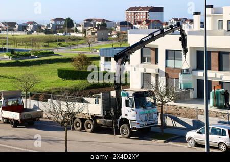 Pritschenwagen, der Glasscheiben mit einem LKW-montierten Kran zu einem neuen Wohnblock Santander Cantabria Spanien liefert Stockfoto