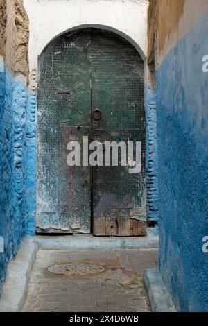 Fes, Marokko. Farbenfrohe blaue Wände und alte Tür in einer der vielen Gassen in der Medina. Stockfoto