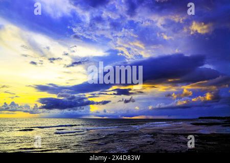 Das goldene Licht der untergehenden Sonne reflektiert ein goldenes Leuchten am Strand am Pererenan Beach, während die Wellen auf Bali, Indonesien, hereinbrechen Stockfoto