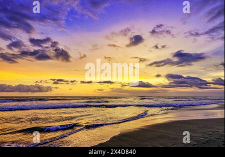 Das goldene Licht der untergehenden Sonne reflektiert ein goldenes Leuchten am Strand am Pererenan Beach, während die Wellen auf Bali, Indonesien, hereinbrechen Stockfoto