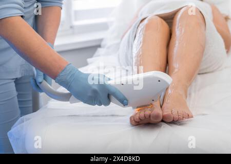 Eine Frau unterzieht sich einer Fotoepilierung in einem Schönheitssalon und vertraut einem Kosmetikologen auf die Haarentfernung mit Laser. Ein Experte für Kosmetologie führt durch Stockfoto