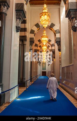 Ein Mann, der im Männerbetszimmer der Sultan-Qaboos-Moschee, Maskat, Oman läuft. Stockfoto