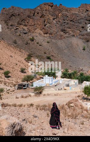 Eine Frau geht zu ihrem Haus in Wadi Al Arbeieen, Oman. Stockfoto