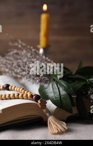 Rosenkranzperlen, Bibel und Weidenzweige auf dem Tisch, Nahaufnahme Stockfoto