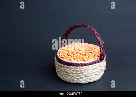 Rote Linsen stapeln sich isoliert. Trockene orangene Linsenkörner, Haufen von Dal, roh Daal, Dhal, Masoor, Lens culinaris oder Lens esculenta auf Jutekorb. Stockfoto