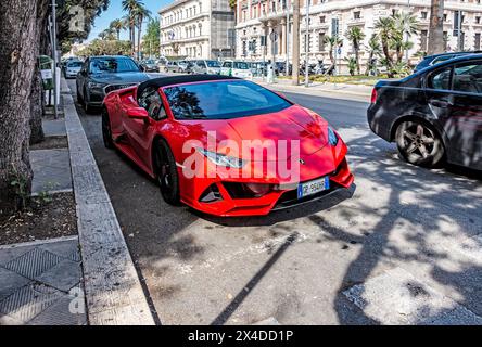 Red Lamborghini Sportwagen parkt entlang einer von Bäumen gesäumten Stadtstraße in Bari, Italien. Stockfoto