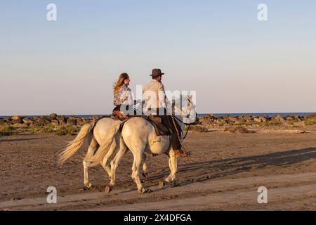 Saintes-Maries-de-la-Mer, Bouches-du-Rhone, Provence-Alpes-Cote d'Azur, Frankreich. Mann und Frau reiten Pferde in der Camargue. (Nur Für Redaktionelle Zwecke) Stockfoto