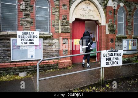 Frau, die am Wahltag eine walisische Wahlstation betritt, mit zweisprachigen Schildern. Wahl des Polizeikommissars. Südwales. Mai 2024 Stockfoto