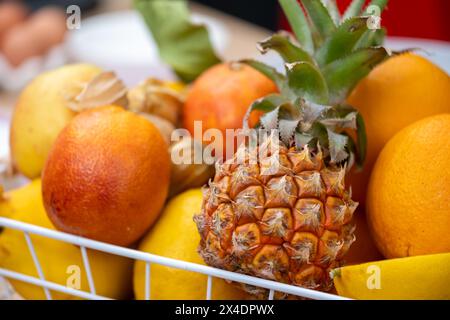 Früchte, reife Ananas, frische Orangen und gelbe Bananen, ordentlich in einem Drahtkorb angeordnet, demonstrieren die ansprechende Vielfalt und Frische, Nährstoffe Stockfoto