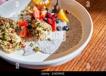 Chia-Pudding mit hausgemachtem Kokosnussgranola, Erdnussbutter und Beeren in einer grauen Schüssel. Gesunde pflanzliche Ernährung, Entgiftung, Sommerrezept. Frühstück im Stockfoto