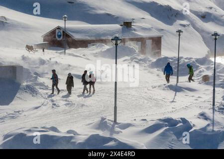 Menschen, die an einem windigen Tag in einer Straße spazieren. Ilulissat, Grönland. Stockfoto