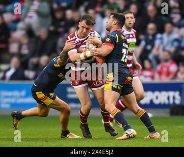 Harry Smith von Wigan Warriors wird von Ben Garcia von Catalan Dragons und Tariq Sims von Catalan Dragons während des Spiels der Betfred Super League Runde 10 Wigan Warriors gegen Catalans Dragons im DW Stadium, Wigan, Großbritannien, 2. Mai 2024 (Foto: Craig Thomas/News Images) Stockfoto