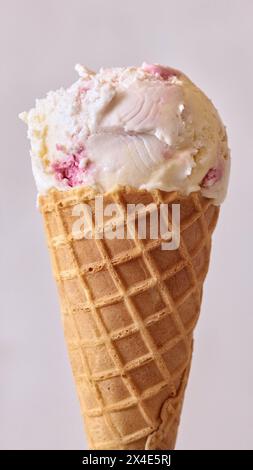 Eiskugel mit frischem Vanille- und Erdbeergeschmack oder Himbeergeschmack in Waffelkegel isoliert auf hellem Hintergrund Stockfoto