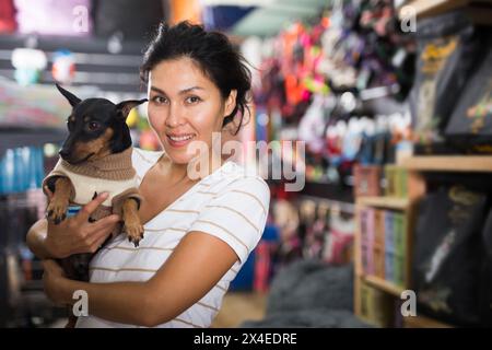 Porträt einer lächelnden Frau mit seinem Hund in Winterkleidung, die den Heimtierbedarf besucht Stockfoto
