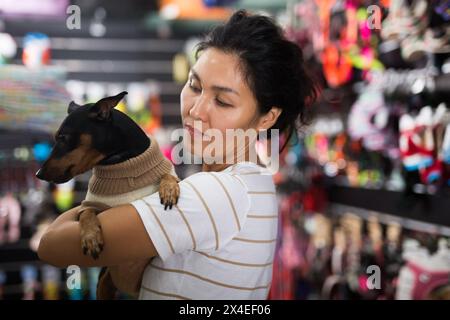 Porträt einer lächelnden Frau mit seinem Hund in Winterkleidung, die den Heimtierbedarf besucht Stockfoto