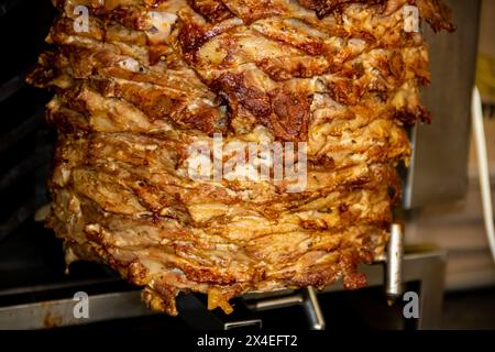 Gyros: Saftige, gewürzte Fleischscheiben, perfekt gegrillt, in eine warme Pita gewickelt, mit frischen Tomaten, Zwiebeln und cremiger Tzatziki-Sauce garniert Stockfoto