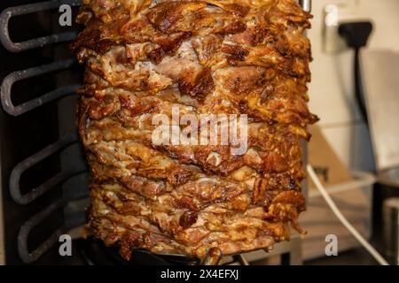 Gyros: Saftige, gewürzte Fleischscheiben, perfekt gegrillt, in eine warme Pita gewickelt, mit frischen Tomaten, Zwiebeln und cremiger Tzatziki-Sauce garniert Stockfoto