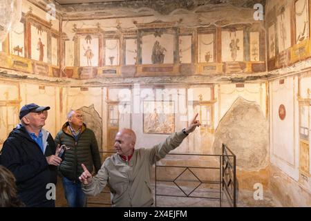 Pompeji Tourismus; Ein Reiseleiter, der eine Führung durch die Fresken im Haus der Vettii Villa gibt; Pompeji Reise, UNESCO-Stätte, Pompeji römische Ruinen Stockfoto