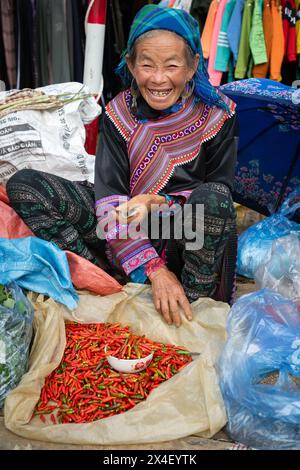 Schwarze Hmong-Frau verkauft Chilis auf dem Cau-Markt in Lao Cai, Vietnam Stockfoto