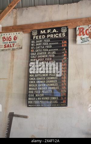 Spencer, MO, USA, 4-13-24. Ein altes Schild hängt im Futter- und Saatgutladen in der restaurierten Stadt Spencer. Das Schild zeigt alte MFA-Preise. Stockfoto