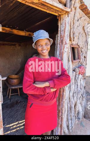 afrikanisches Dorf, alleinerziehendes Teenager-Mädchen vor der Tür draußen, Schlammhütten innen schmutzige Wände Stockfoto