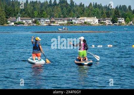 Issaquah, Bundesstaat Washington, USA. Zwei Frauen knien auf ihren Paddleboards, plaudern und paddeln am Sammamish-See. (Nur für redaktionelle Zwecke) Stockfoto