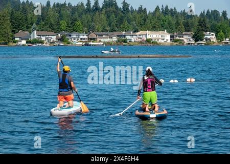 Issaquah, Bundesstaat Washington, USA. Zwei Frauen knien auf ihren Paddleboards, plaudern und paddeln am Sammamish-See. (Nur für redaktionelle Zwecke) Stockfoto