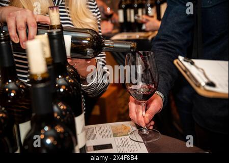 USA, Washington State, Woodinville. Frau gießt Rotwein in ein Glas bei einer Weinveranstaltung in Washington. Stockfoto