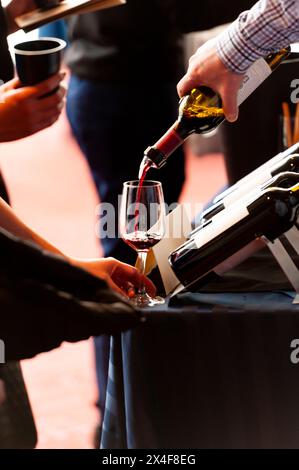 USA, Washington State, Walla Walla. Ein Mann gießt Rotwein in ein Glas bei einer Weinveranstaltung in Walla Walla. Stockfoto