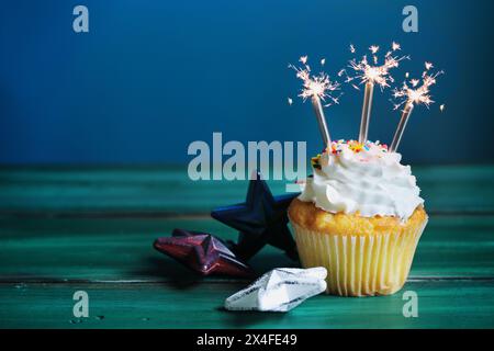 Feier eines Vanille-Cupcake mit Buttercremefüllung, verziert mit Zuckerstreuseln und Sparklern am 4. Juli. Selektiver Fokus mit verschwommenem b Stockfoto